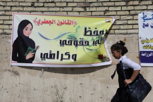 Una niña pasa cerca de un cartel que dice “la Ley Jaafari de estatus personal salva mis derechos y mi dignidad” / AP